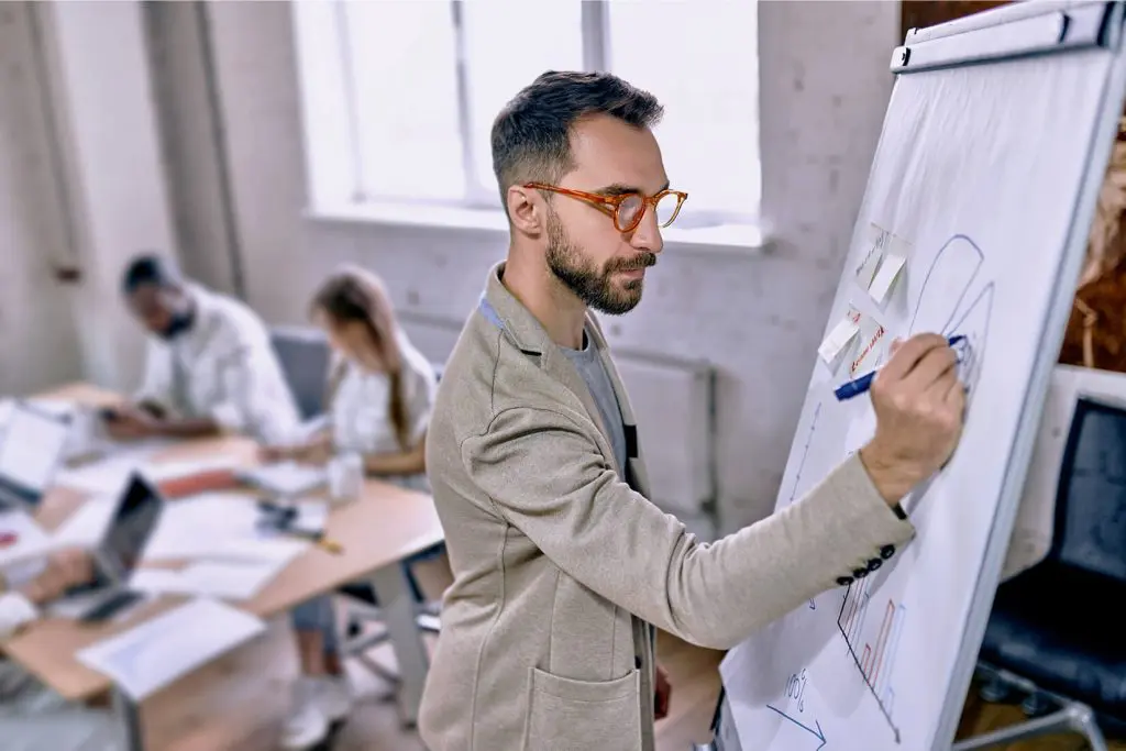 Man writing on white board during meeting