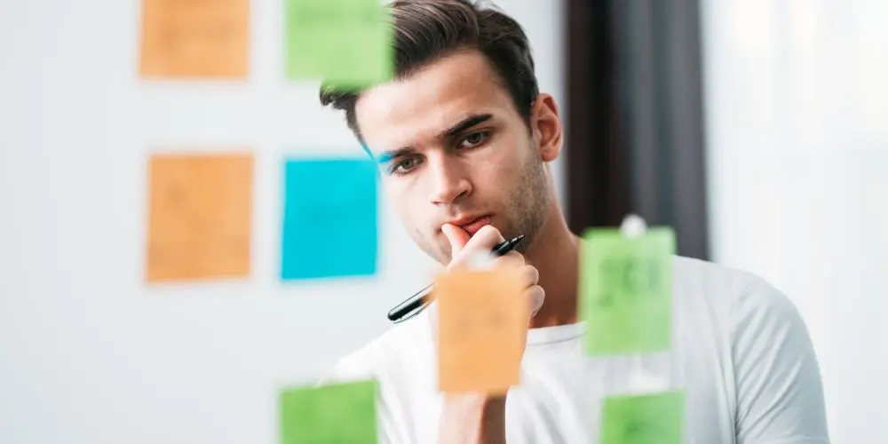 Photograph of man looking at sticky notes on a transparent board